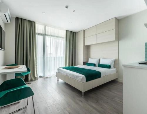 a bedroom with a bed with green sheets and a desk at Green side in Kvariati