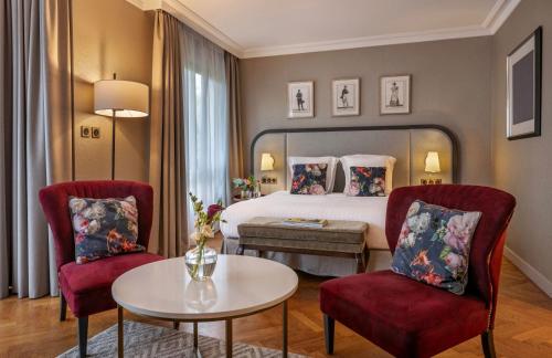 a hotel room with a bed and two chairs and a table at Warwick Reine Astrid - Lyon in Lyon
