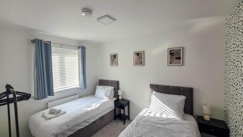 a bedroom with two beds and a window at Spacious and Modern 4BR with Hot Tub and Garden in Peterborough