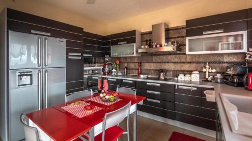 a kitchen with a red table and a refrigerator at Villa Neraida - Panoramic Lake View Retreat in Neráïdha