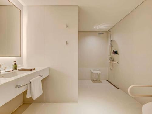 a white bathroom with a sink and a shower at Hotel Grand Tela Suite Delhi in Gurgaon