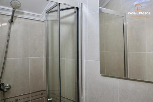 a shower with a glass door and a mirror at Casa dos Passos 1 in Guarda