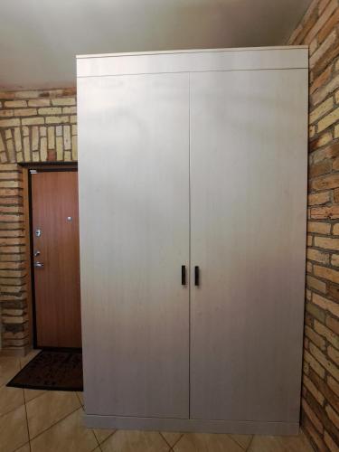 a white cabinet in a room with a brick wall at Cozy apartment in Jeruzalė in Vilnius