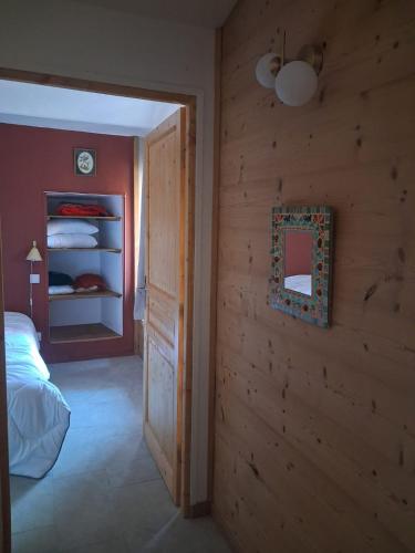 a bedroom with a wooden wall with a bed and a mirror at Gîte Le Pic Epeiche in Saint-Roman