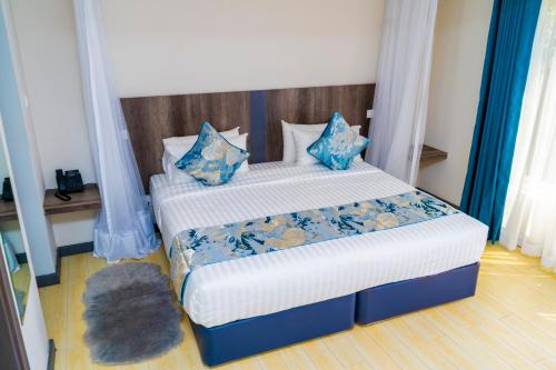 a bedroom with two beds with blue pillows at Ngolu Hotel and Residences in Kitui