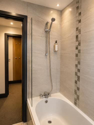 a bath tub in a bathroom with a shower at The Bromley's in Great Yarmouth