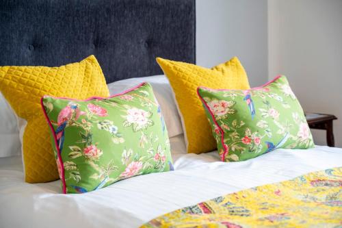 a group of pillows on a bed with yellow pillows at Squirrel Away Apartments in Crieff