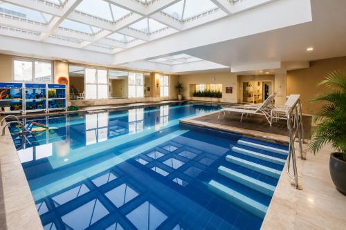 an indoor pool with a large blue swimming pool at Lapidare Flat Hotel Comfor Alphaville até 4 pessoas in Barueri