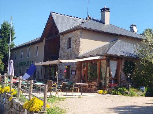 a building with a table and chairs in front of it at Hôtel Restaurant Le Regimbal in Javols
