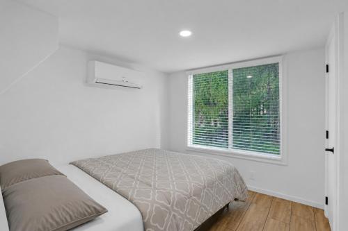 a white bedroom with a bed and a window at Tiny Blue at Yosemite Gateway in Groveland