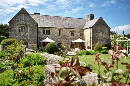 a large stone house with a garden in front of it at The Great House Hotel in Bridgend