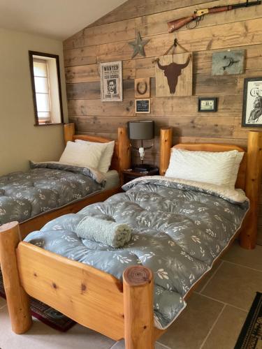 two twin beds in a room with wooden walls at Oak ridge cabin in Norwich