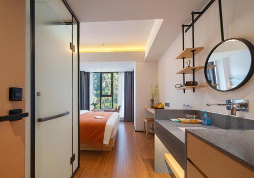 a bedroom with a bed and a bathroom with a mirror at Zhangjiajie Utopia Hotel-New Hotel,English Speaking Host,Free Shuttle Service to East Gate of forest park,Free Fresh Coffee&Tea,Free Self-Service Laundry & Drying, Super-Large Swimming Pool,Tourism Service, Family and Group-friendly in Zhangjiajie