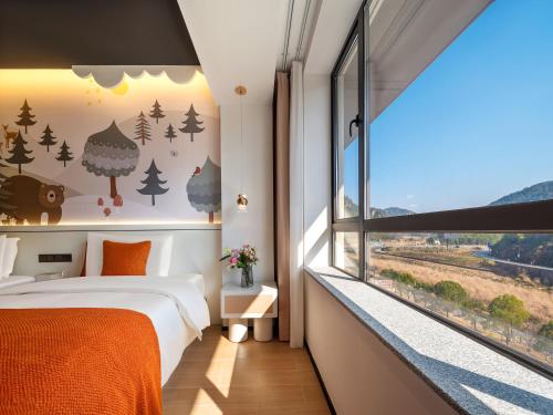 a bedroom with a bed and a window at Zhangjiajie Utopia Hotel-New Hotel,English Speaking Host,Free Shuttle Service to East Gate of forest park,Free Fresh Coffee&Tea,Free Self-Service Laundry & Drying, Super-Large Swimming Pool,Tourism Service, Family and Group-friendly in Zhangjiajie