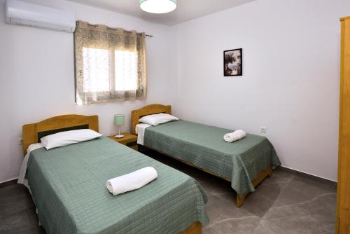 two beds in a room with green sheets at Stegna Holiday 2 in Archangelos