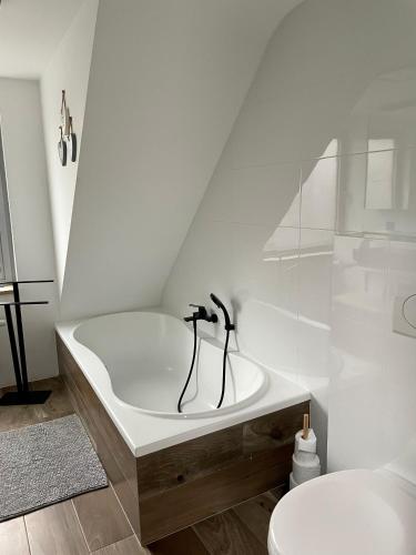 a white bathroom with a bath tub and a toilet at Duplex appartement in rustige woonwijk in Mortsel
