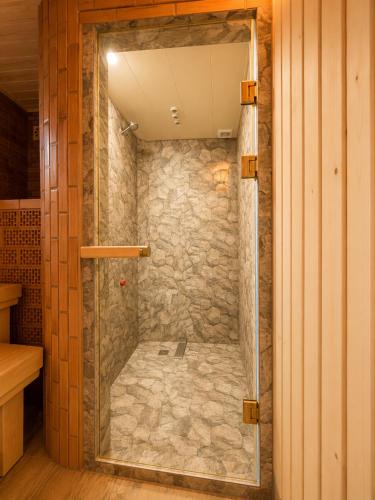 a walk in shower with a stone wall at Green Garden in Batumi