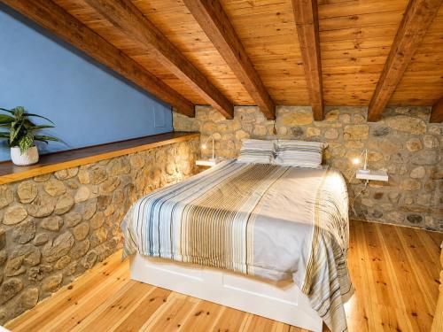 a bedroom with a bed in a stone wall at La Cochera del Abuelo in Medina de Pomar
