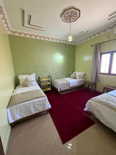 a room with two beds and a red carpet at Comfortable Luxury House in Merzouga
