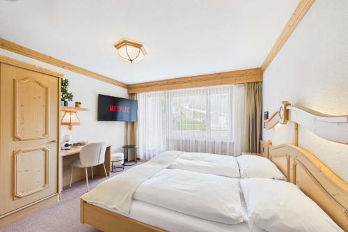 a bedroom with a bed and a desk and a window at Suite with Mountain View near Saas-Fee in Saas-Almagell