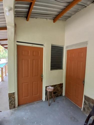 two orange doors in a room with a stool at A 7 min de Palmerola, Aire acondicionado, Wifi y Parqueo in Comayagua