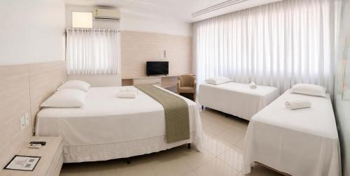 a hotel room with two beds and a television at Hotel Residence in Caruaru