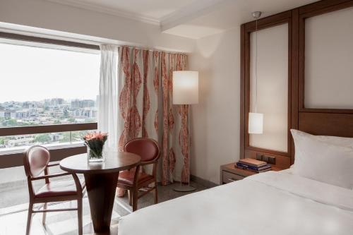 ラゴスにあるEko Hotel Main Buildingのベッド、テーブル、窓が備わる客室です。