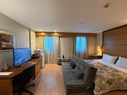 a bedroom with a bed and a desk and a television at Hotel Wynd Ibirapuera 512A in São Paulo