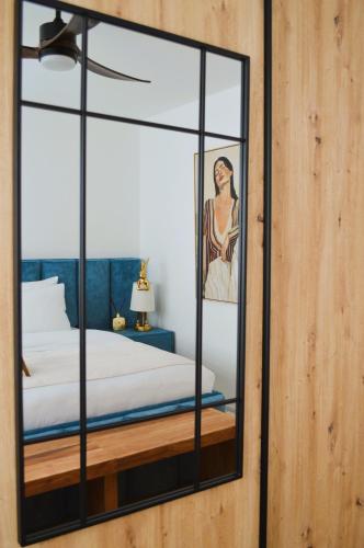 a mirror in front of a bed with a picture of a woman at Apartman Vera in Prijedor