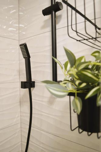 a black shower wand next to a plant at Apartman Vera in Prijedor