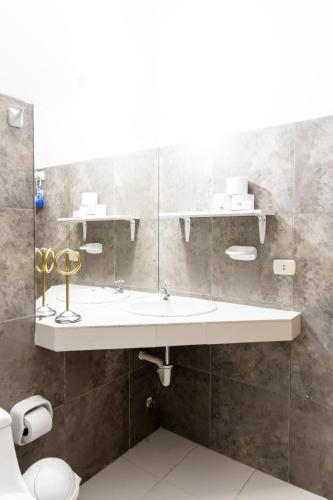 a bathroom with a sink and a mirror at Hosteria Suiza in Ica
