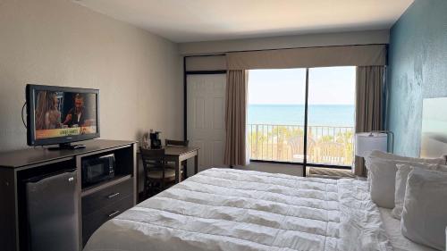 a bedroom with a bed and a television and a balcony at Atlantic Crest Inn and Suites in Myrtle Beach
