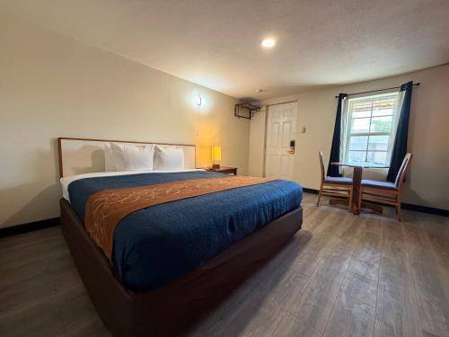 a bedroom with a bed and a desk and a window at Ponca Motel in Abilene