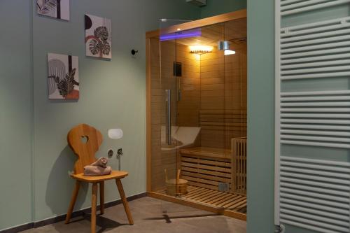 a bathroom with a shower and a wooden chair at Hotel al Dòs - Breakfast & Private SPA in Trento