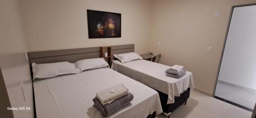 two twin beds in a room with a mirror at hOTEL CALIFORNIA in Barreiras