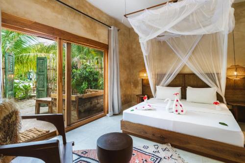 ein Schlafzimmer mit einem Bett und einem großen Fenster in der Unterkunft Oke Ani Boutique Hotel in Paje