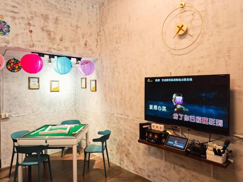 a room with a table with chairs and a tv at Mumian Manlv Homestay in Hengchun South Gate