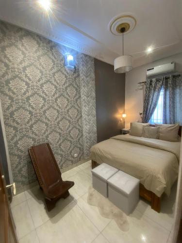 a bedroom with a bed and a chair at La Bienveillance in Brazzaville