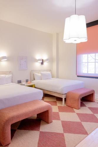 a bedroom with two beds and benches in it at Quirk Hotel Richmond in Richmond