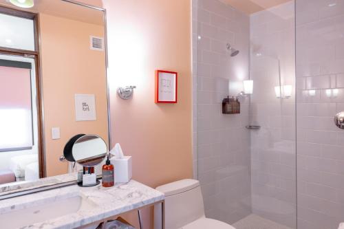 a bathroom with a shower and a toilet and a sink at Quirk Hotel Richmond in Richmond