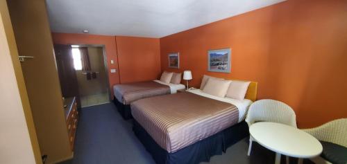 ein Hotelzimmer mit zwei Betten und einem Tisch in der Unterkunft Avalon Inn in Osoyoos
