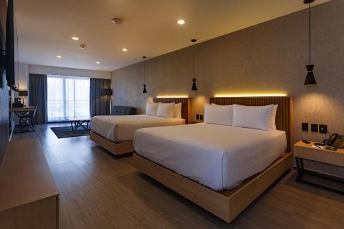 a hotel room with two beds and a desk at Hotel Luure Bosque Real in Mexico City