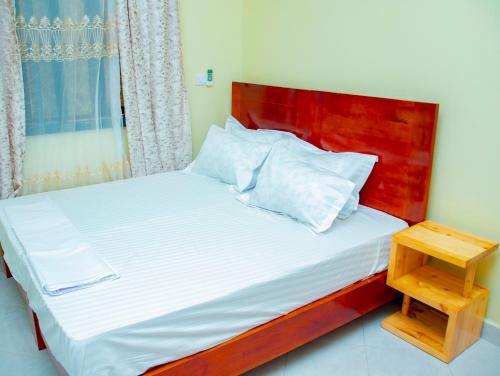 a bed with a wooden headboard and a night stand at Umoja Backpacker's Stay in Msaranga