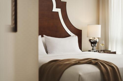 a bedroom with a white bed with a wooden headboard at L'Hermitage Hotel in Vancouver