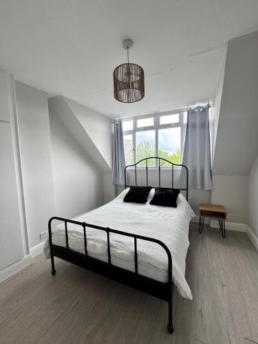 a bedroom with a bed with white sheets and black pillows at Ultra cozy in Brookmans Park