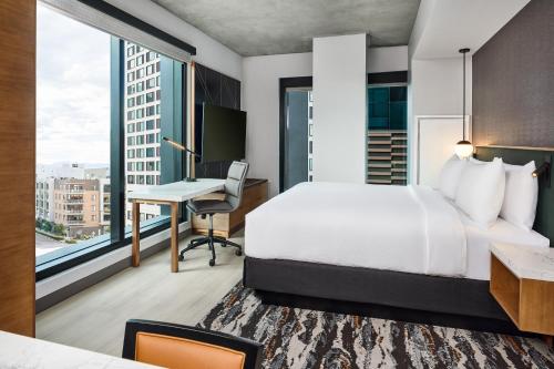 a hotel room with a bed and a desk and window at Apiary Hotel Belleview Station Denver in Denver