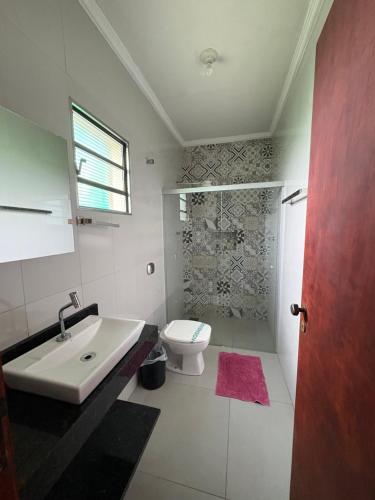 a white bathroom with a toilet and a sink at Pousada Os Galeguinhos in Santa Cruz do Rio Pardo