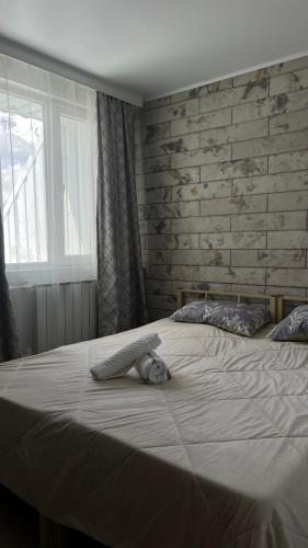 a bedroom with a large white bed and a brick wall at Эталон АПАРТ-ОТЕЛЬ Aqtobе in Aktobe
