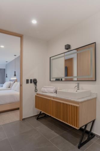 a bathroom with a sink and a mirror and a bed at Hotel Luure Bosque Real in Mexico City