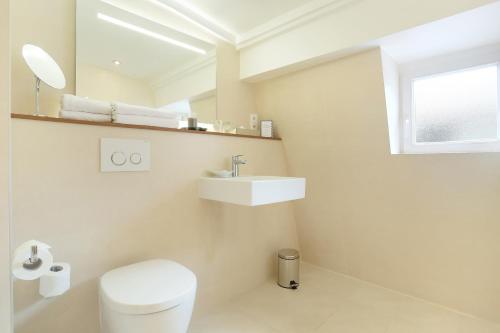 a white bathroom with a toilet and a sink at Maison Axel Opéra Paris in Paris